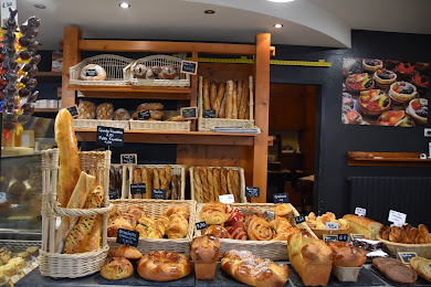 L'intérieur de la boulangerie : baguettes en corbeille, pains et viennoiseries sur les présentoirs